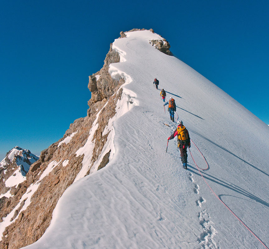 Photo de plusieurs alpinistes grimpant un sommet enneigé