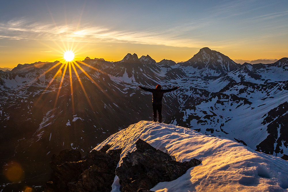 Photo d'une personne regardant un coucher de soleil en montagne
