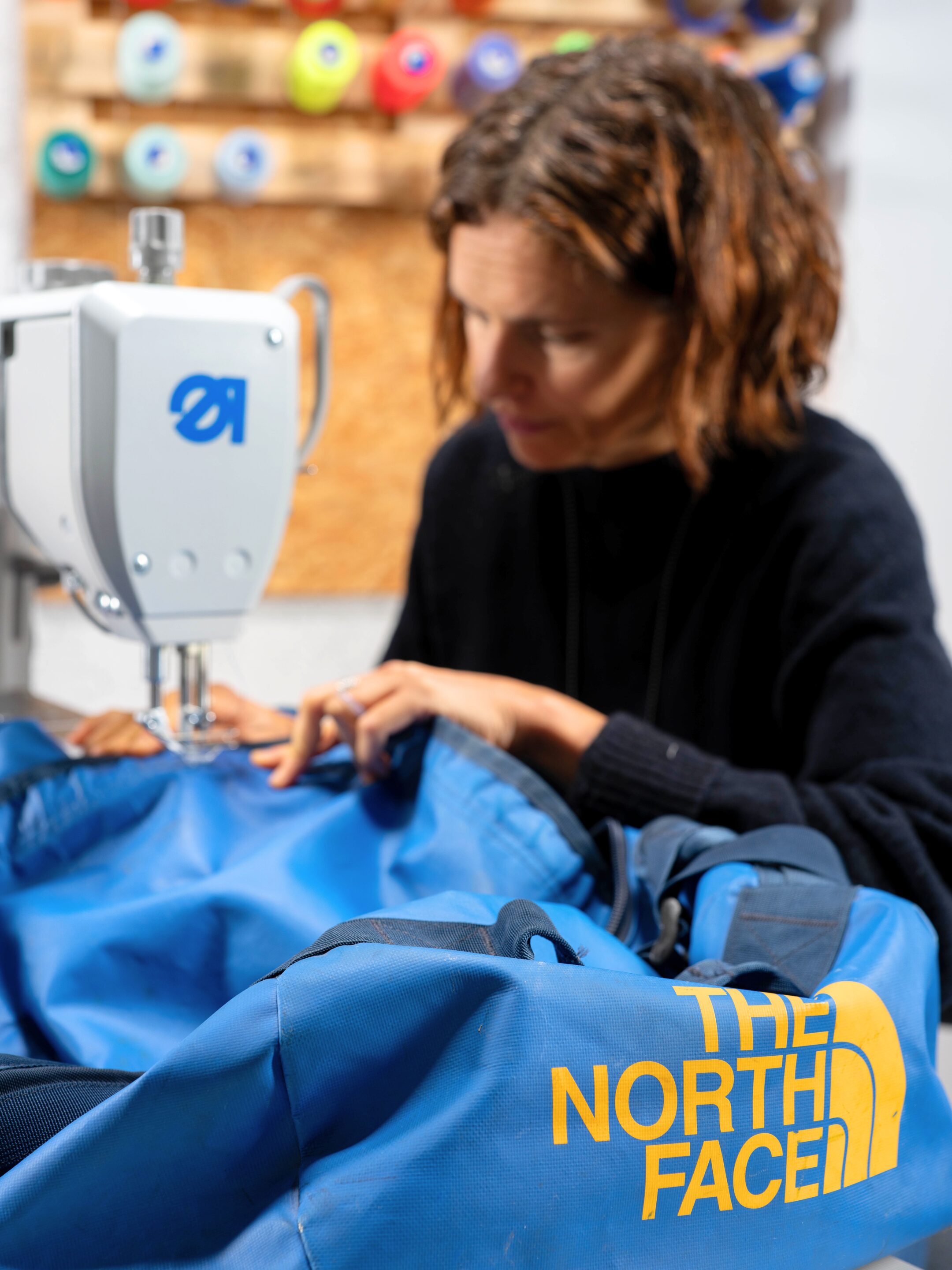 Une couturière Goodloop répare un sac The North Face dans l’atelier.