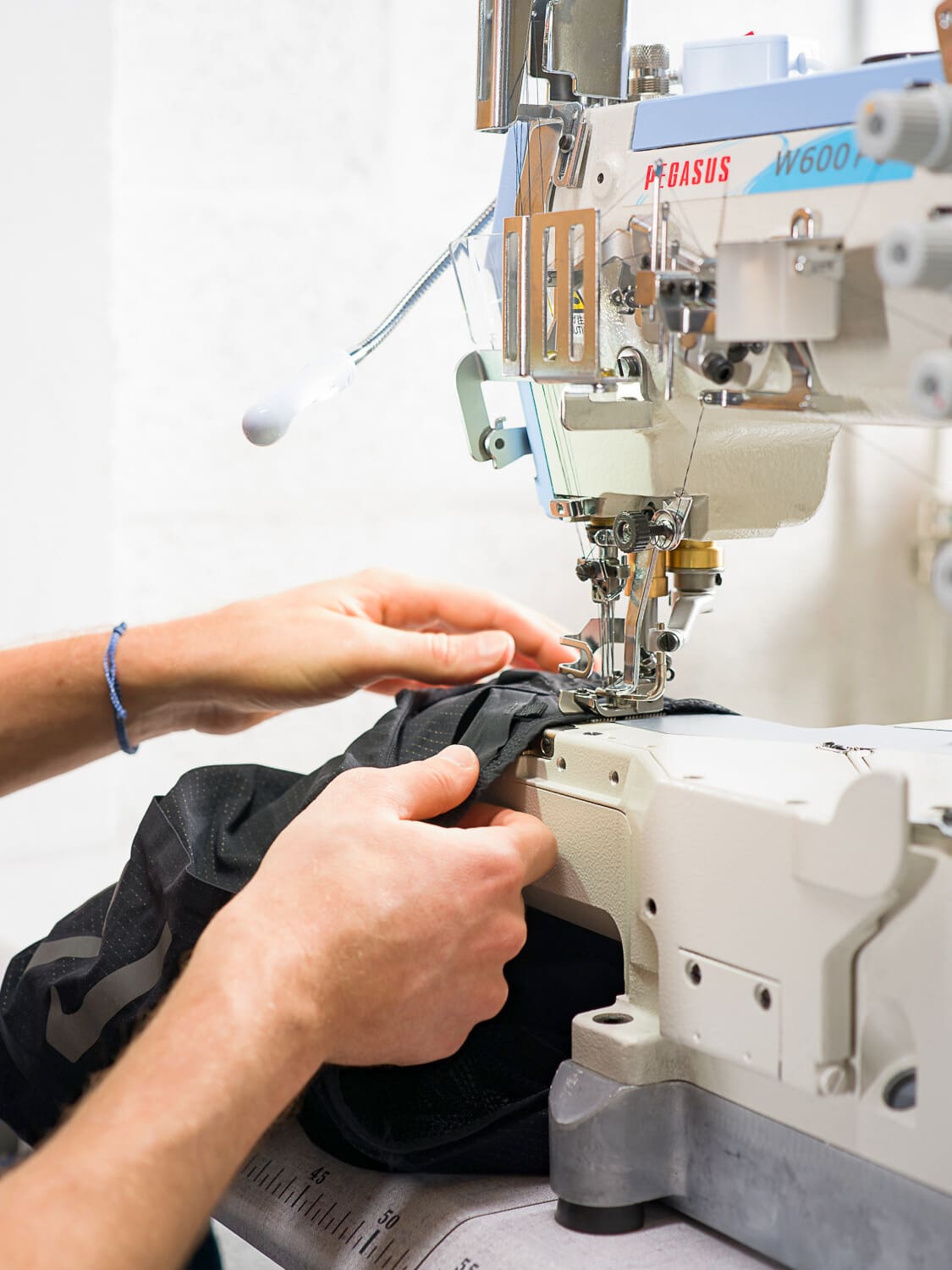 Main d’un couturier en train de réparer une matière cycliste sur une machine technique dans l’atelier Goodloop.