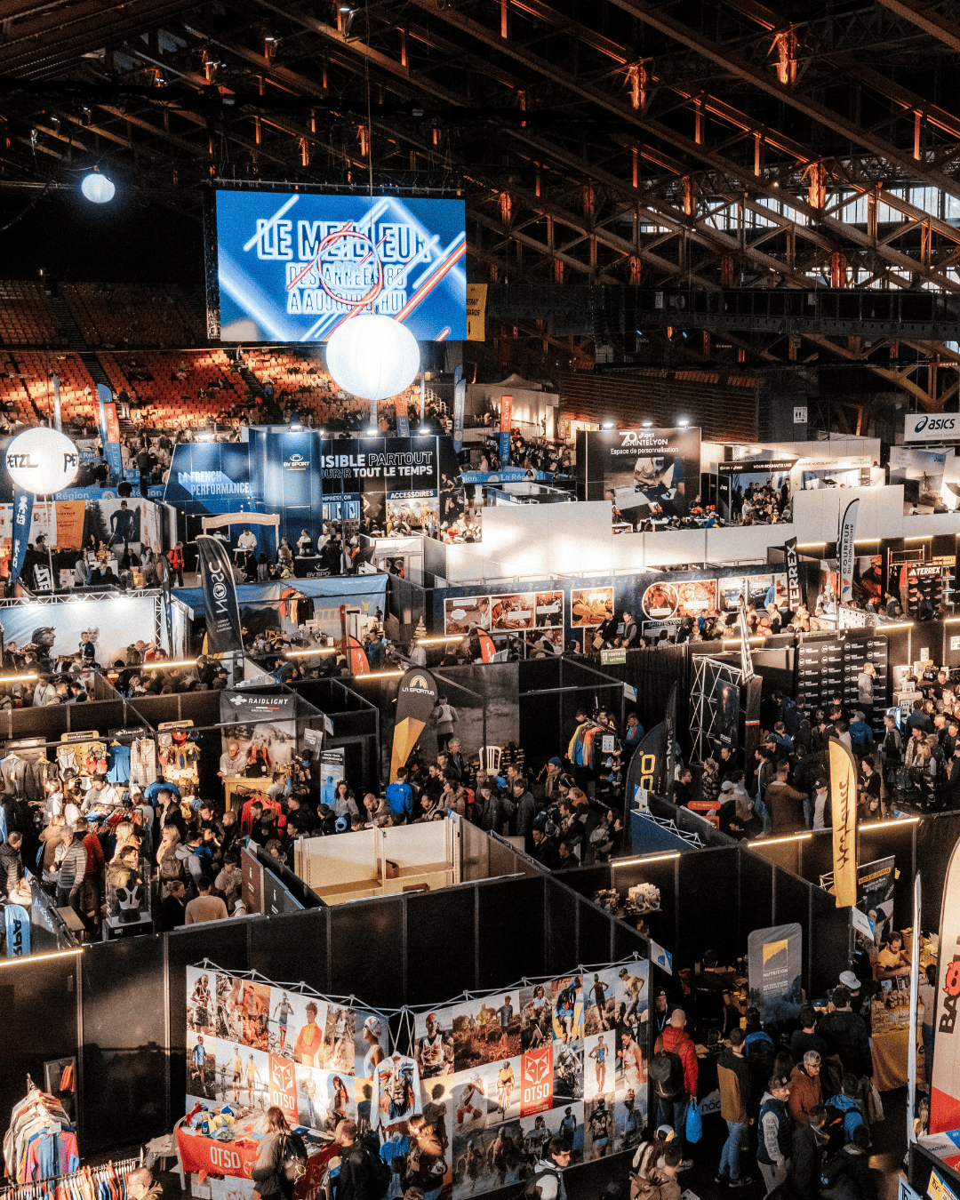 Vue d’ensemble du salon trail running à Lyon organisé dans le cadre de la Asics SaintéLyon, avec de nombreux stands et visiteurs.

