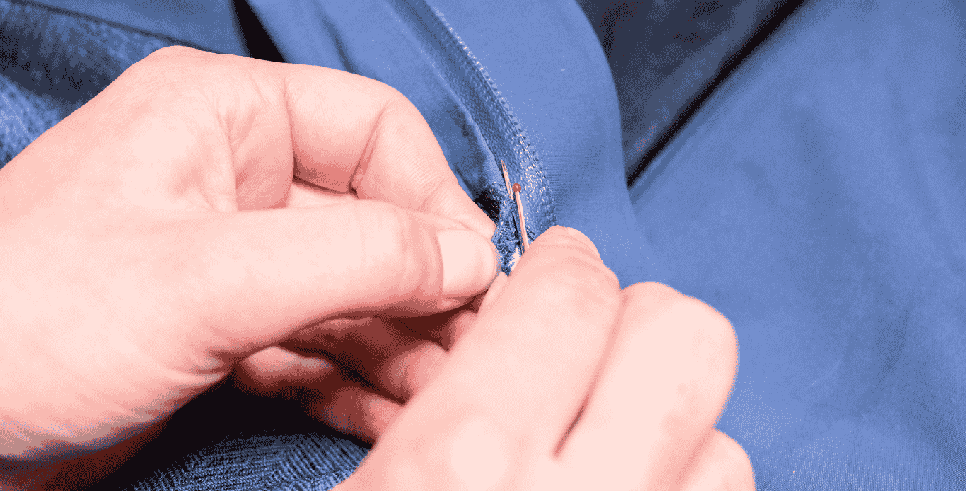 Réparation d’une fermeture éclair cassée Fermeture éclair cassée en train d’être décousue avant réparation sur une veste