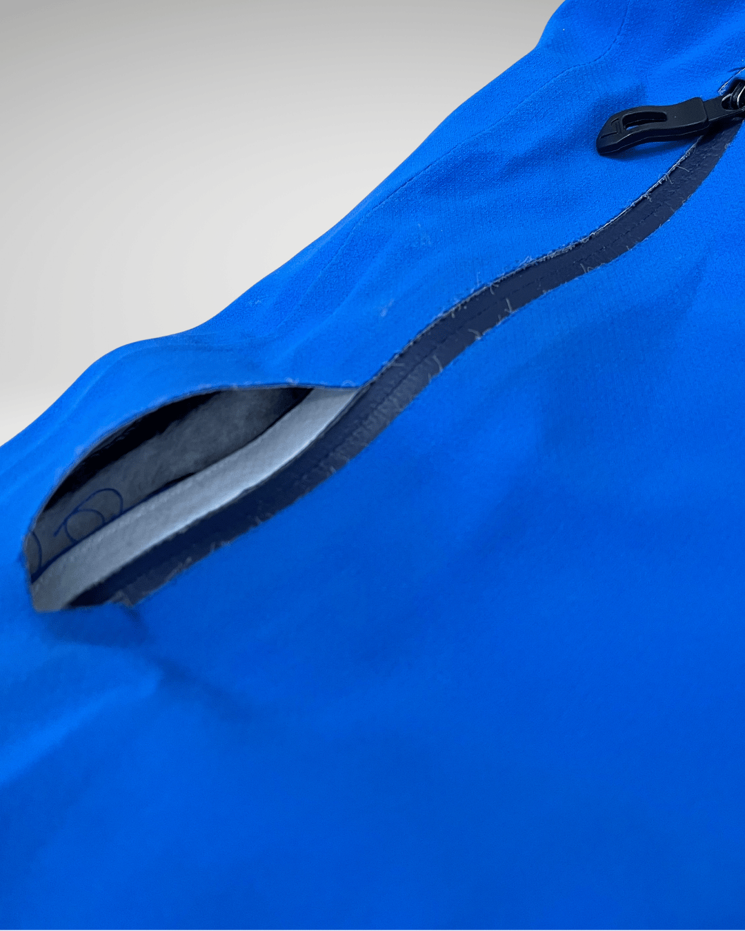 Poche thermocollée de veste technique qui se décolle autour de la fermeture éclair avant intervention