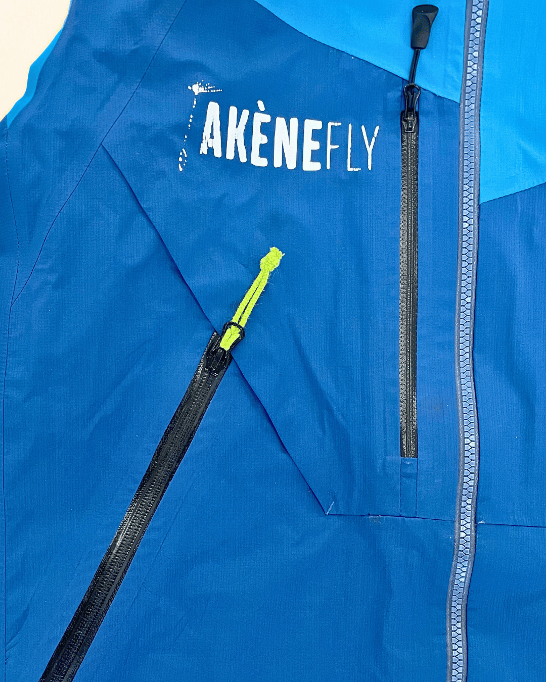Veste imperméable bleue avec deux fermetures éclair de poches et un curseur réparés après intervention Goodloop.