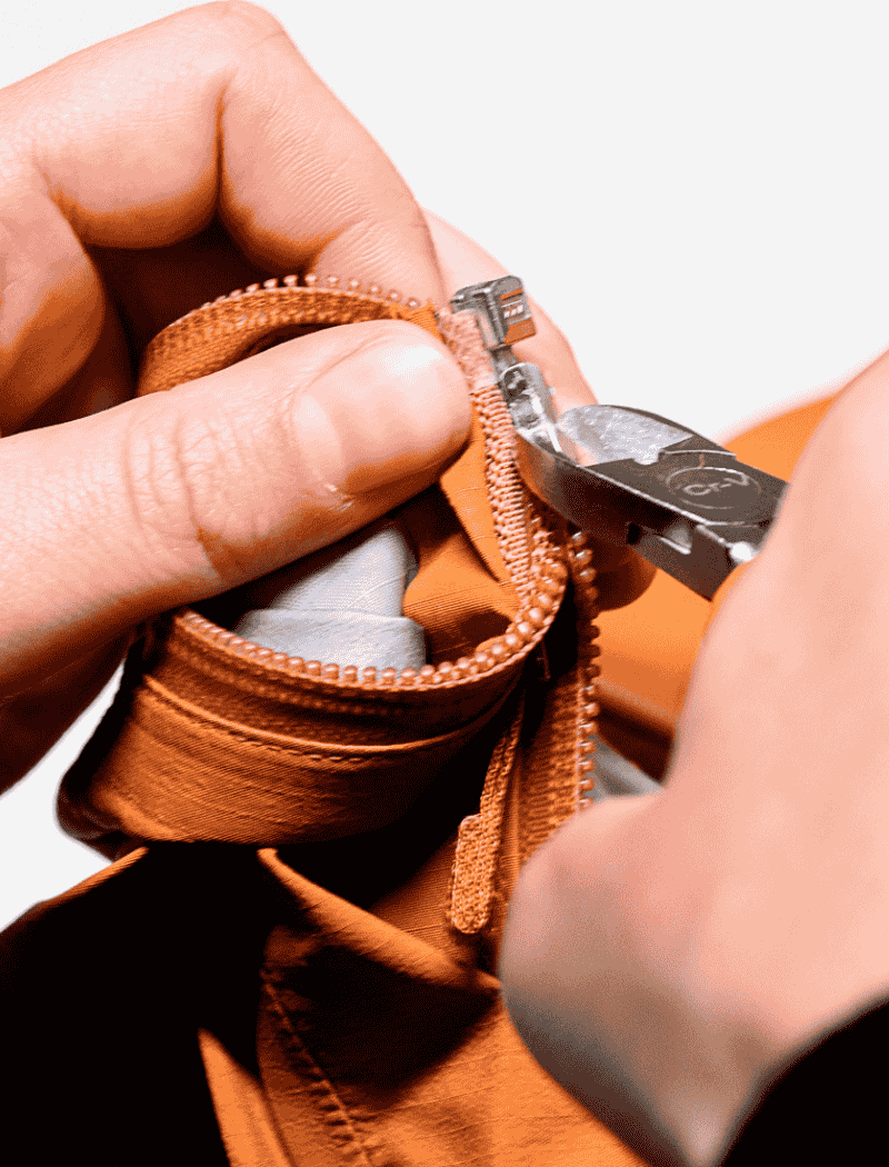 Reparation curseur fermeture eclair veste Gore Tex Goodloop Réparation du curseur d’une fermeture éclair sur une veste technique Gore-Tex à l’aide d’une pince dans l’atelier Goodloop.