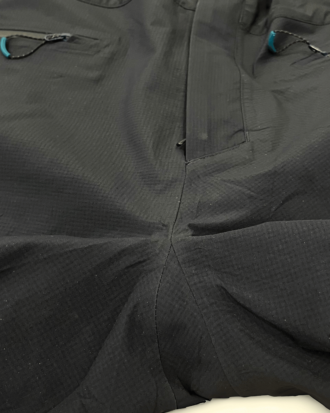 Entrejambe de pantalon de ski réparé avec des coutures renforcées et étanchéité restaurée.