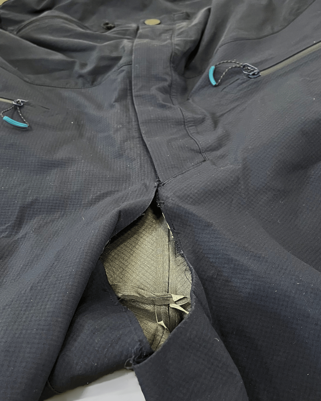 Pantalon de ski déchiré ou décousu au niveau de l'entrejambe avant réparation.