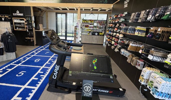 Intérieur du magasin Run Aventure à Béziers avec un tapis de course, montrant le comptoir où les sportifs peuvent déposer leurs vêtements et équipements pour réparation