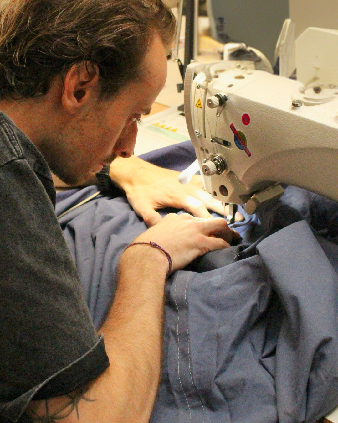 Couturier Goodloop réparant le zip d’une tente canadienne utilisée par un groupe scout dans l’atelier.