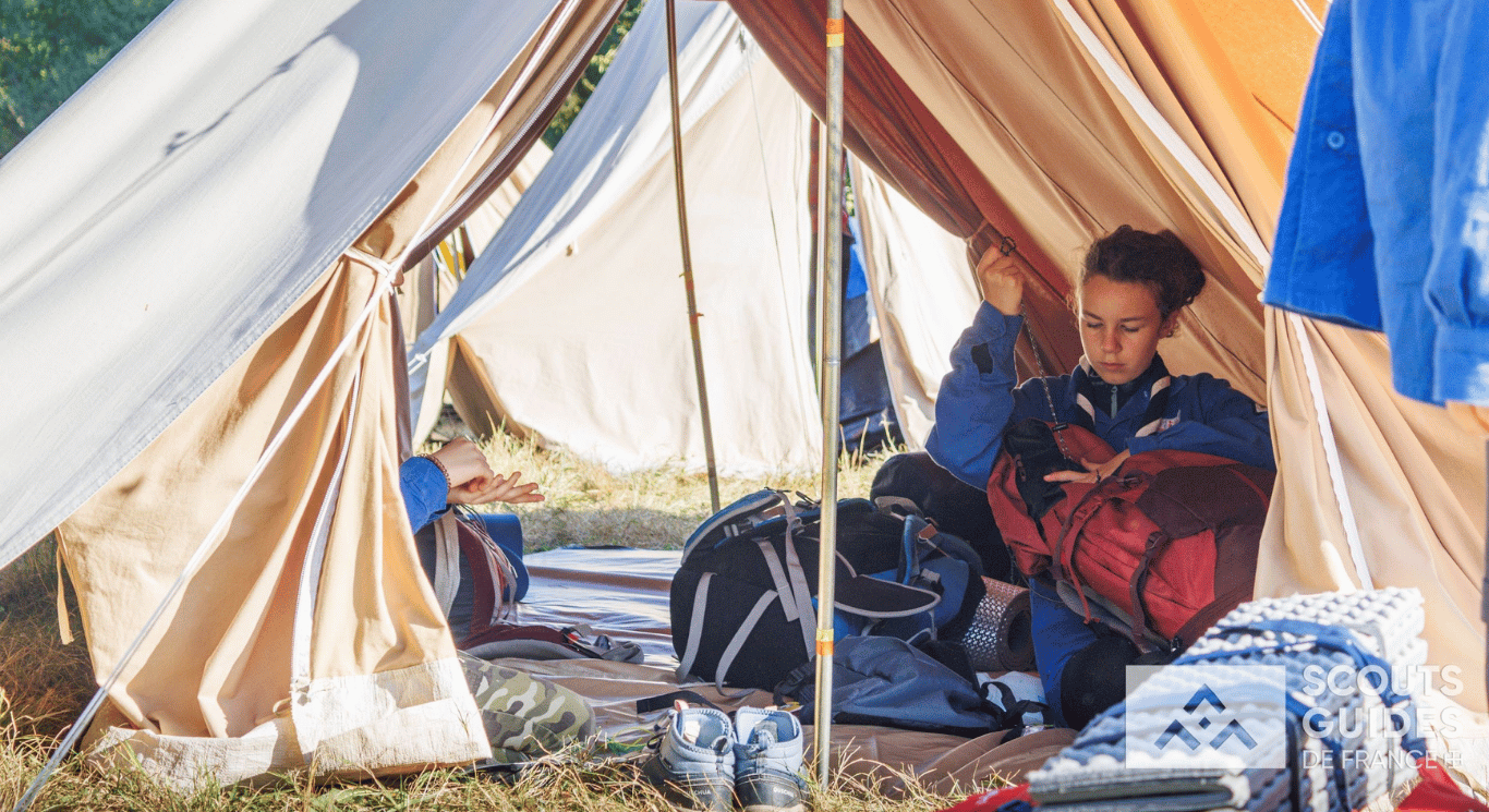 Jeune fille scout préparant son sac à l’intérieur d’une tente canadienne réparée